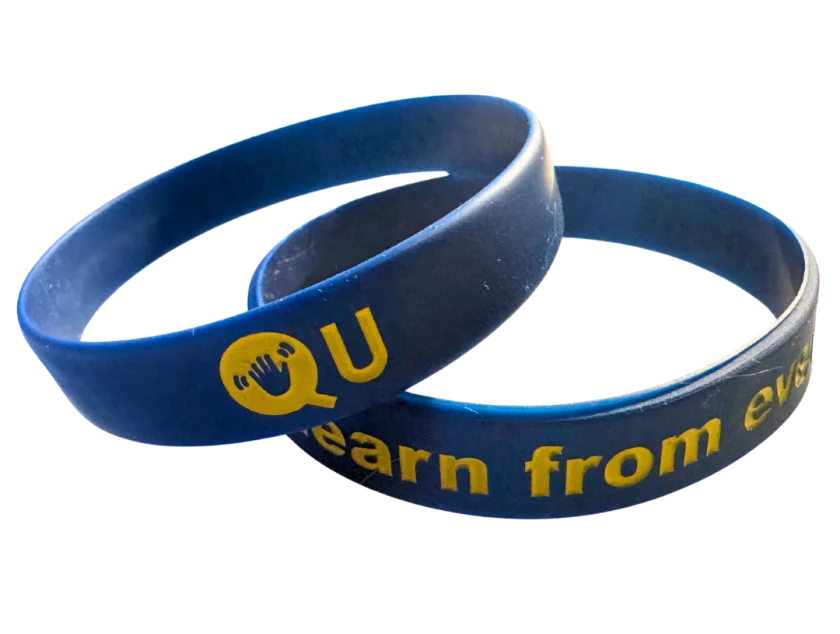 Two navy Qu wristbands reading Learn from every moment